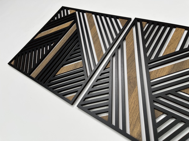 May include: Two black geometric wall decor panels with a wood grain pattern. The panels are made of thin strips of wood that are arranged in a geometric pattern. The panels are designed to be hung on a wall.