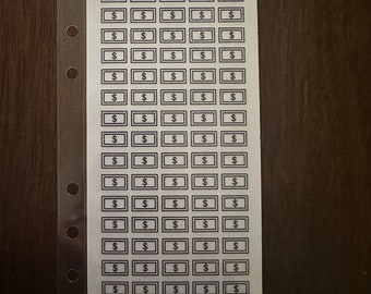 May include: A white sheet with a $1 Savings Challenge printed on it. The sheet has 80 dollar signs arranged in a grid. The text "$80 Saved When Completed" is printed at the bottom of the sheet.