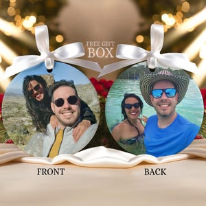 May include: Two round ornaments with photos, each with a white ribbon for hanging. One shows a couple smiling, labeled "FRONT." The other shows a couple in water, labeled "BACK." The text "FREE GIFT BOX" is above the ornaments.