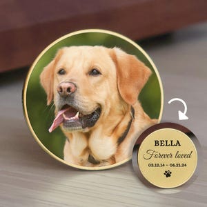 May include: A golden-colored dog portrait in a round, gold-rimmed frame. A smaller, matching round pendant displays the name "Bella", the phrase "Forever loved", dates, and a paw print. The dog has a pink tongue.
