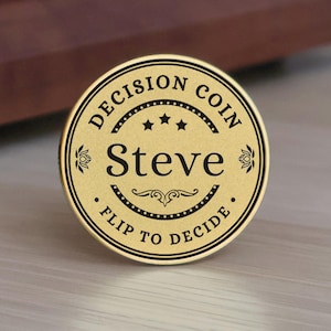 May include: A gold-colored decision coin with black text. The coin reads "DECISION COIN" at the top, "Steve" in the center, and "FLIP TO DECIDE" at the bottom. The coin has a decorative border and is likely used for making choices.