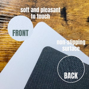 May include: A white mouse mat with a soft, smooth surface on the front and a black, textured, non-slip surface on the back. The text "FRONT" is printed on the white surface and the text "BACK" is printed on the black surface. The text "soft and pleasant to touch" is printed above the white surface and the text "non-slipping surface" is printed above the black surface.