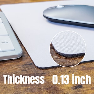 May include: White mouse mat with a black stitched edge. The mouse mat is 0.13 inches thick and has a textured surface.
