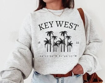 May include: Gray sweatshirt with black text that reads "KEY WEST" and a graphic of palm trees. The text also includes the coordinates "24°33'55" N 81°46'33" W".