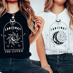 Op de afbeelding: Twee vrouwen dragen zwarte en witte t-shirts met een maan- en zonontwerp. Het zwarte shirt zegt "The Coven" en het witte shirt zegt "The Bride".