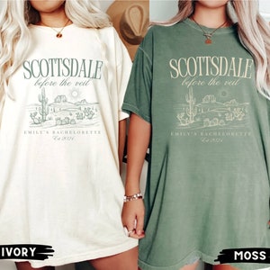 May include: Two oversized t-shirts, one ivory and one moss green, featuring the text "SCOTTSDALE before the veil" above a desert landscape illustration. Below the illustration is "EMILY'S BACHELORETTE Est 2024".