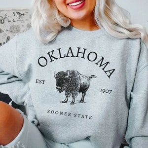 May include: Gray sweatshirt with a black graphic of a buffalo and the text "OKLAHOMA EST 1907 SOONER STATE".