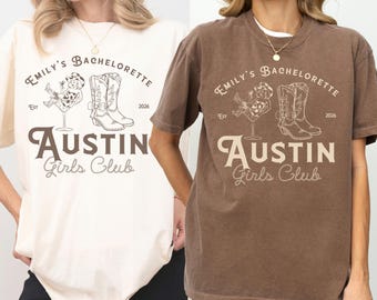 May include: Two t-shirts, one cream and one brown, featuring the text "Emily's Bachelorette Austin Girls Club" with a graphic of a woman in a cocktail glass and cowboy boots. The shirts have a relaxed fit.