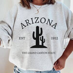 May include: Gray sweatshirt with black text that reads "Arizona Est 1912 The Grand Canyon State" and a graphic of two cacti.
