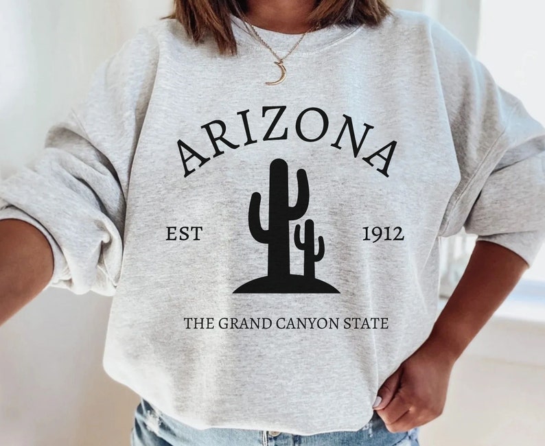 May include: Gray sweatshirt with black text that reads "Arizona Est 1912 The Grand Canyon State" and a graphic of two cacti.