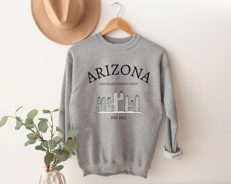 May include: Gray sweatshirt with a black graphic design that says "Arizona, The Grand Canyon State, Est 1912" with a drawing of cacti.