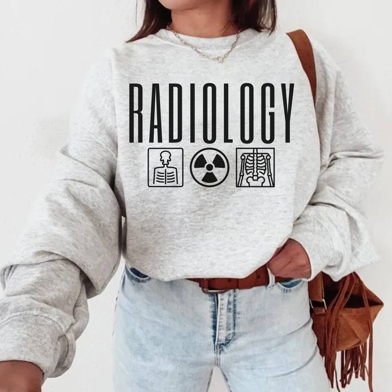 May include: A grey sweatshirt with the word "RADIOLOGY" printed in black. The sweatshirt has three black icons: a skeleton, a radiation symbol, and an x-ray image of a skeleton.