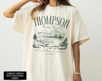 Könnte beinhalten: Elfenbeinfarbenes T-Shirt mit forstgrünem Text und Grafik. Der Text lautet "THOMPSON Family Reunion LAKE ARROWHEAD, GEORGIA EST 2026". Die Grafik zeigt eine See-Szene mit Bergen und Bäumen.