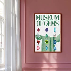 May include: A framed print titled "MUSEUM OF GEMS" in green lettering. The artwork features a collage of various gemstones, each labeled with text. The gemstones are arranged around a central figure with outstretched arms.