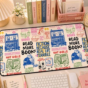 May include: A rectangular desk mat with a cream background and a repeating pattern of book-related illustrations and text. The text includes phrases like "Read More Books" and "Bookstore Hot Girls". A keyboard, mouse, and notebook are also visible.