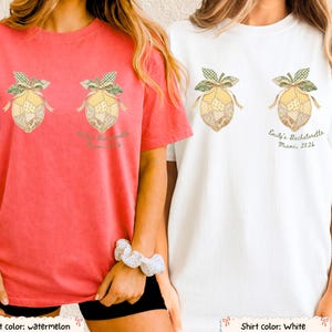 Puede incluir: Dos camisetas, una sandía y otra blanca, cada una con un diseño de limón y un lazo. La camiseta blanca tiene el texto "Emily's Bachelorette Miami, 2026". La camiseta sandía tiene el mismo diseño y texto. Ambas son de manga corta.