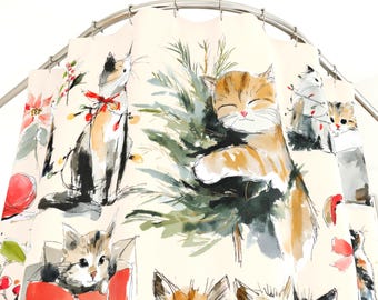 Puede incluir: Una cortina de ducha con un diseño de acuarela caprichoso de gatitos juguetones. Los gatos se representan en varias poses, algunos con adornos navideños y un árbol de Navidad. La paleta de colores incluye tonos de naranja, negro, blanco y verde sobre un fondo crema.