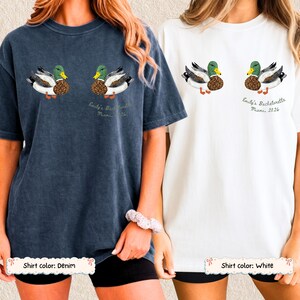 May include: Two short-sleeve crewneck t-shirts, one in denim blue and one in white, each featuring a graphic of two mallard ducks and the text "Emily's Bachelorette Miami 2026" printed in a script font below the right-hand duck illustration.