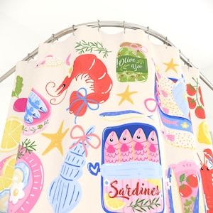 May include: A cream-colored shower curtain featuring a colorful pattern of seafood and Mediterranean food items, including a red shrimp, a jar labeled Olive You, a blue tin labeled Sardines, yellow starfish, lemon slices, and tomatoes.