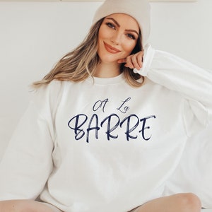May include: White sweatshirt with a navy blue graphic that says "A La Barre" in a cursive font.