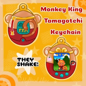May include: A keychain shaped like a Tamagotchi, featuring a cartoon monkey king character. The keychain is red and gold with a screen showing the monkey king in a forest setting. The text "They Shake!" is visible in the image.