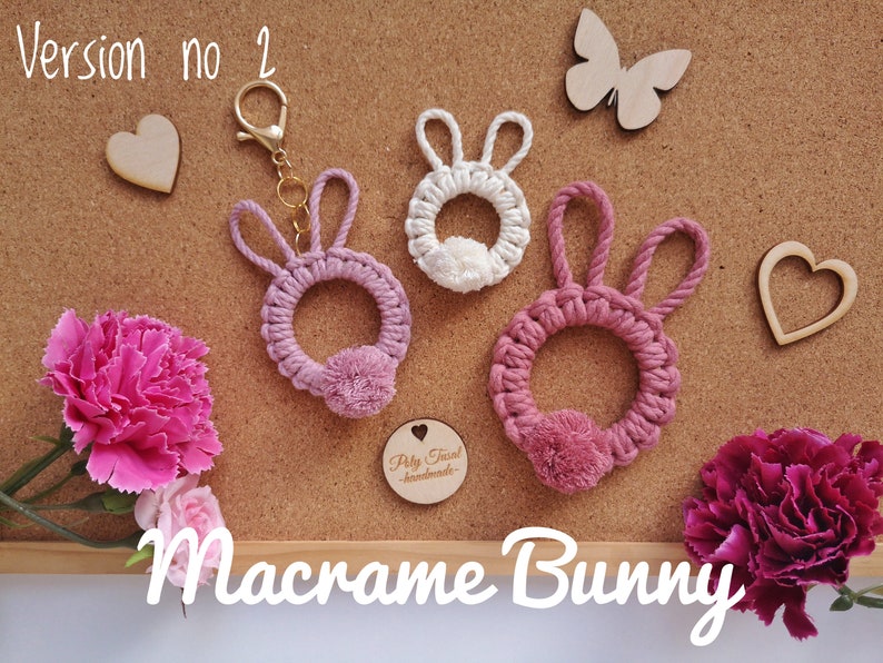Pink macrame rabbits pendants with thin ears at cork board, next to flowers, Easter plywood hearts, butterflies. White Macrame Bunny Title. Version no 2 in the left top corner.