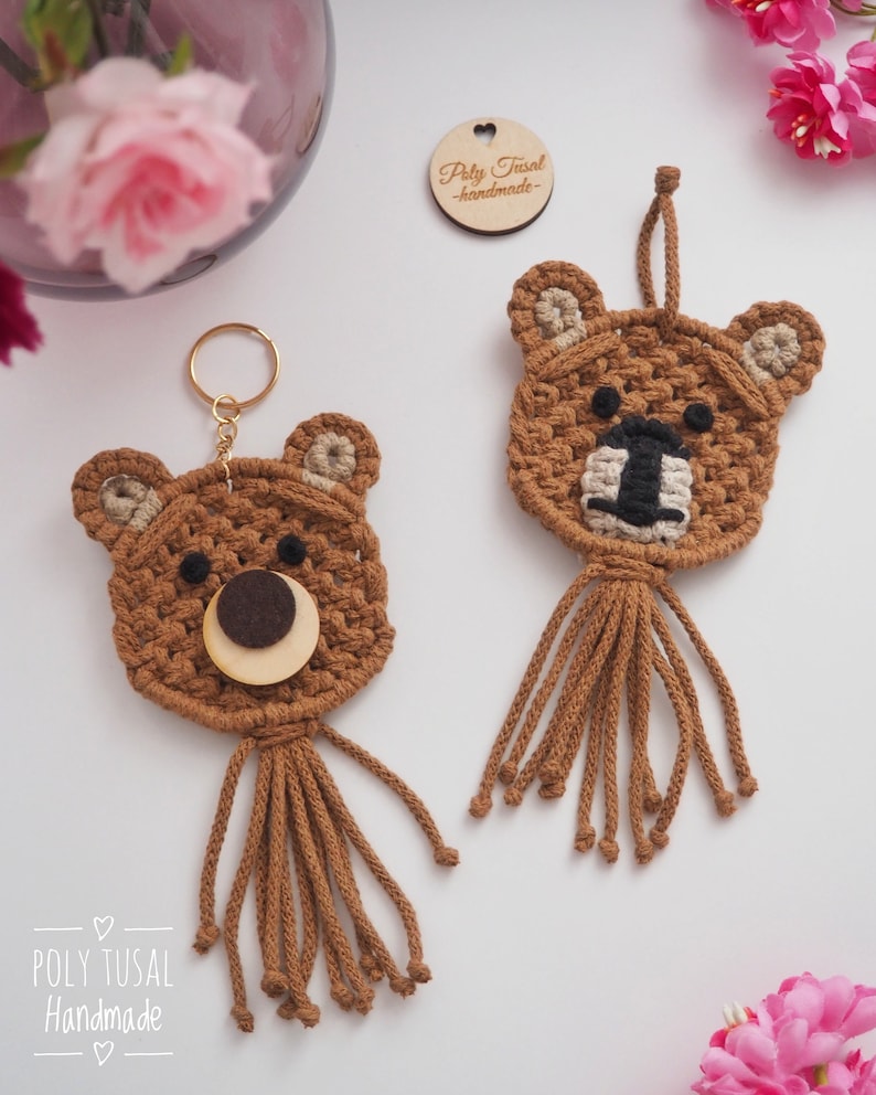 May include: Two handmade brown crochet bear keychains and a bear ornament. The keychains have gold rings, and the ornament has a hanging loop. Each bear has a tan snout, black nose, and brown tassels. A wooden tag with text is also visible.