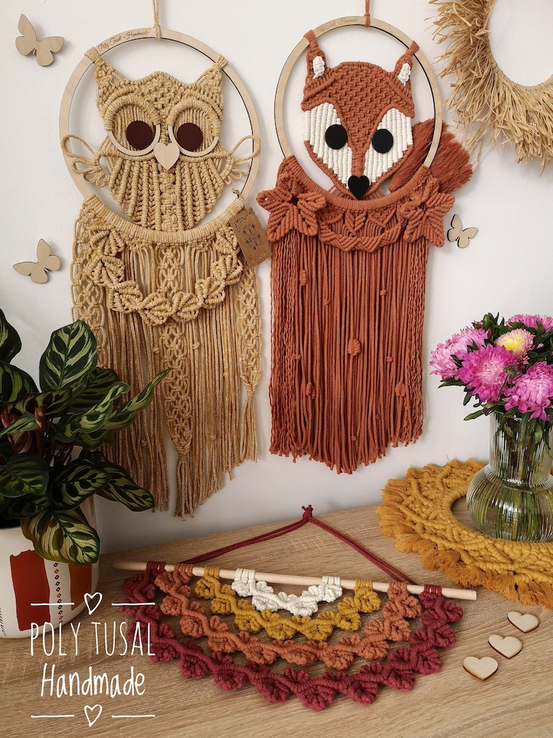 Yellow Macrame Owl and Red Macrame Fox are hanging on the wall between the flowers. Warm colors version of Macrame Leaf Half Mandala is laying on the table.
On the left is logo of Poly Tusal Handmade.