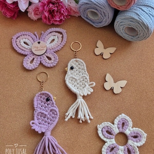 May include: A selection of handmade macrame items, including a butterfly, bird keyrings, and a flower coaster in purple and white. Wooden butterfly shapes and spools of pink and blue yarn are also present. The Poly Tusal Handmade logo is visible.