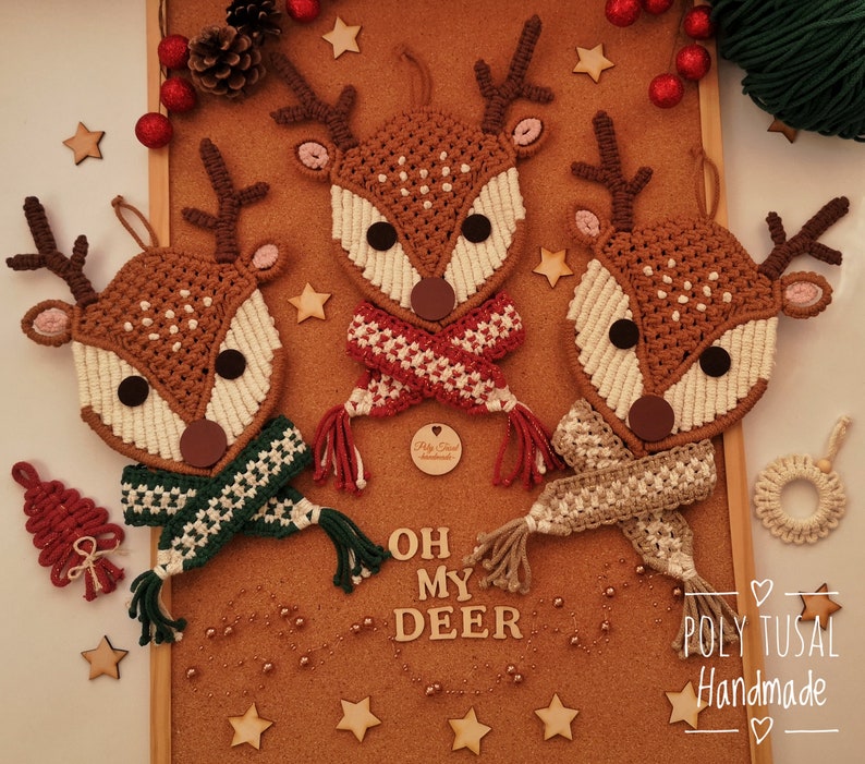 May include: Three handmade macrame reindeer decorations with different coloured scarves. The reindeer are brown with white accents and have black eyes. The scarves are red and white, green and white, and beige. The decorations are on a cork board with the text "Oh My Deer" and "Poly Tusai Handmade" written below.