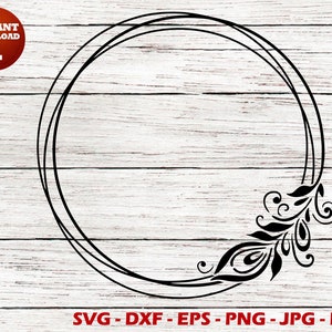 May include: A black and white circular frame with a decorative floral design on the right side. The frame is on a white wood background.