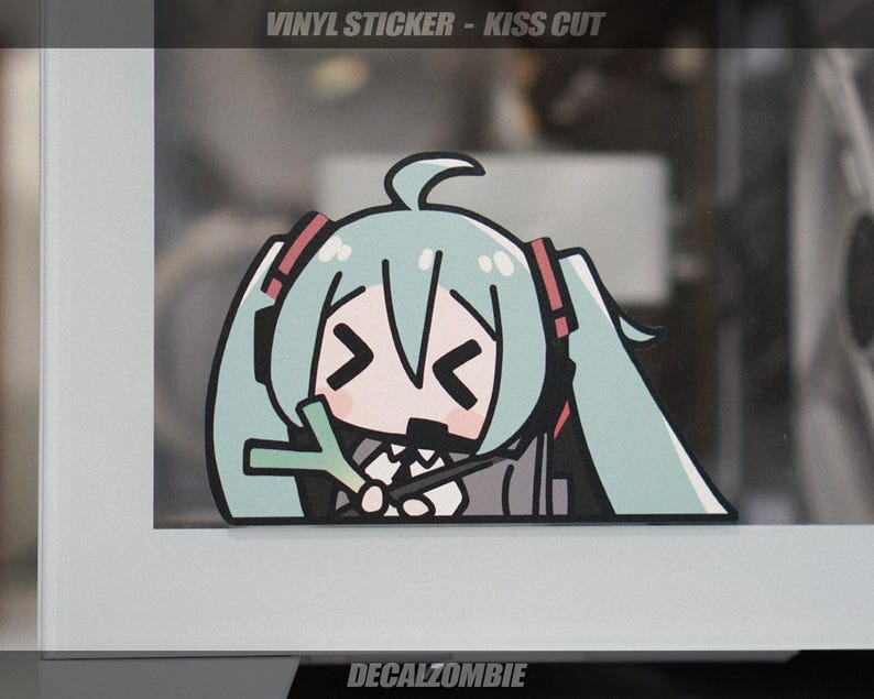 May include: A vinyl sticker featuring a cartoon character with teal hair, red headphones, and a black outfit. The character is holding a microphone. The sticker has the text "VINYL STICKER - KISS CUT" and "DECALZOMBIE".