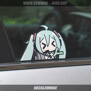 May include: A vinyl sticker featuring a cartoon anime character with light blue hair and a sad expression. The sticker is kiss-cut and applied to a car window. The text "VINYL STICKER - KISS CUT" is at the top, and "DECALZOMBIE" is at the bottom.