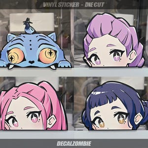 May include: Vinyl die-cut stickers featuring four unique designs. Includes a blue cartoon cat with a bird, and three anime-style character faces with pink, purple, and blue hair. The text "VINYL STICKER - DIE CUT" and "DECALZOMBIE" are visible.