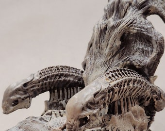 May include: A detailed, off-white sculpture of a creature with a skeletal design. The sculpture features a textured surface, with prominent rib-like structures, skulls, and a large, ornate back piece. The overall design suggests a fantasy or horror theme.