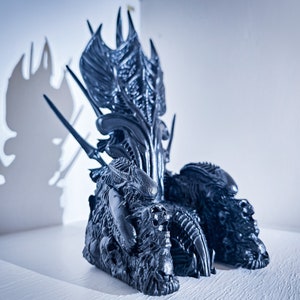 May include: A detailed, dark gray throne with an intricate design, featuring sharp, elongated elements and a textured surface. The chair's back is tall and ornate, with a shadow cast on the wall. The overall theme is fantasy and sci-fi.