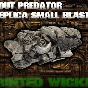 May include: A gray replica small blaster with intricate details, as seen in the image. The text "SCOUT PREDATOR REPLICA SMALL BLASTER" is displayed at the top, and "PRINTED WICKED" is at the bottom. The blaster has a textured, mechanical design.