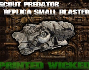 May include: A gray replica small blaster with intricate details, as seen in the image. The text "SCOUT PREDATOR REPLICA SMALL BLASTER" is displayed at the top, and "PRINTED WICKED" is at the bottom. The blaster has a textured, mechanical design.
