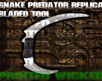 May include: A silver bladed tool with a curved design and a black handle. The text "SNAKE PREDATOR REPLICA BLADED TOOL" is at the top, and "PRINTED WICKED" is at the bottom. The background is a detailed, metallic, industrial design.