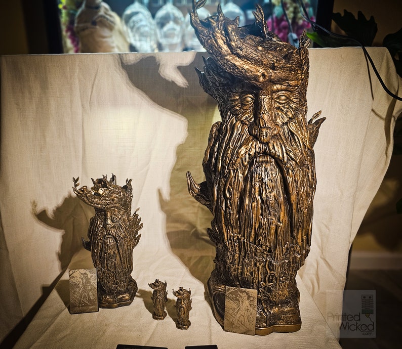 May include: Bronze-colored sculptures of a bearded, tree-like figure with a crown of leaves. The sculptures vary in size, with a large bust and smaller figurines. The figures have detailed textures and are displayed with small cards.