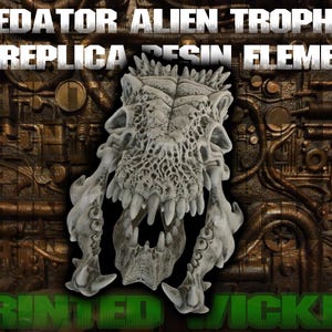 May include: A Predator Alien Trophy replica resin element. The sculpture is a detailed, off-white skull with sharp teeth and intricate bone structure. The background is a textured, metallic surface with the words "PRINTED WICKED" in green.