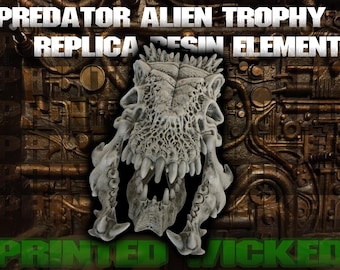 May include: A Predator Alien Trophy replica resin element. The sculpture is a detailed, off-white skull with sharp teeth and intricate bone structure. The background is a textured, metallic surface with the words "PRINTED WICKED" in green.