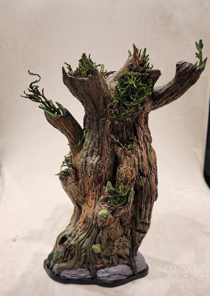 May include: A detailed, hand-painted tree sculpture with a textured, brown bark. Green moss and small plants are nestled in the crevices and branches. The base is dark with a stone-like texture, creating a fantasy or woodland theme.
