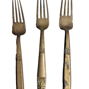 Può includere: Tre forchette antiche in bronzo con rebbi e manici ornati. Le forchette hanno un aspetto vintage, con motivi dettagliati vicino alla base dei rebbi e sui manici. Le forchette sono esposte su uno sfondo bianco.