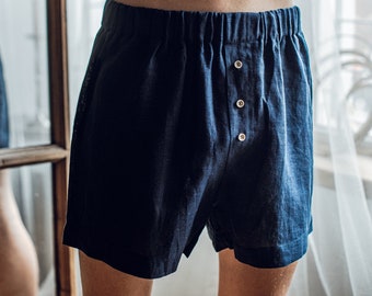 May include: Dark blue linen shorts with a button fly and three buttons. The shorts are made of a soft, comfortable fabric.