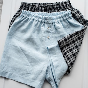 May include: Two pairs of shorts, one light blue and one black and white checked. The light blue shorts have a button fly and an elastic waistband.