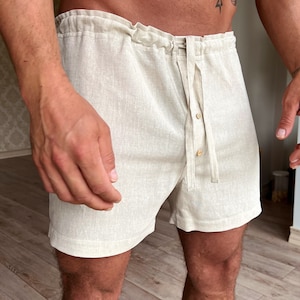 Puede incluir: Shorts de lino beige con cintura de cordón y cierre de botón. Los pantalones cortos tienen un corte holgado y están hechos de una tela ligera.