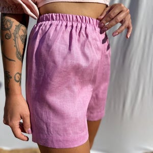 Pu&ograve; includere: Pantaloncini color viola chiaro a tinta unita con vita elasticizzata e un semplice design con orlo sulle gambe. Il capo &egrave; realizzato in un tessuto testurizzato con trama visibile, offrendo una silhouette pulita e lineare per l'uso quotidiano.