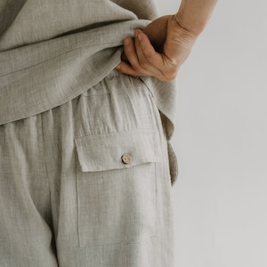 Op de afbeelding: Beige linnen broek met een enkele knoopzak op de achterkant.