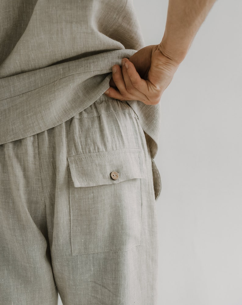 Op de afbeelding: Beige linnen broek met een enkele knoopzak op de achterkant.